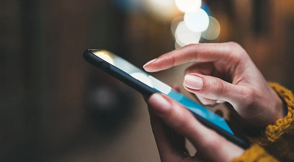 Close up of slender Black hands scrolling through a smart phone at Lone Pine Dental in Bend, OR